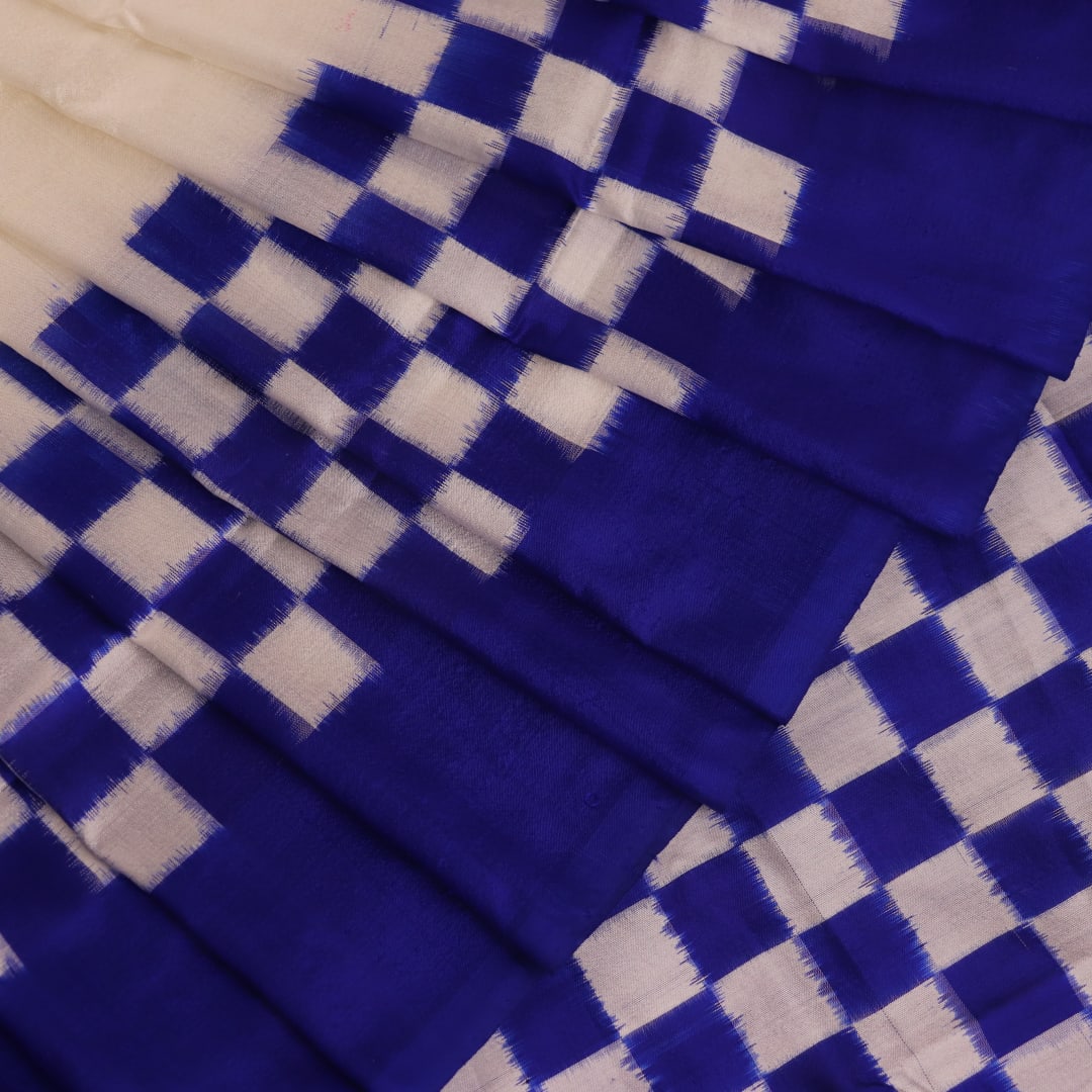 Close-up of the intricate Pasapalli pattern woven on a luxurious white silk Sambalpuri saree with blue accents.