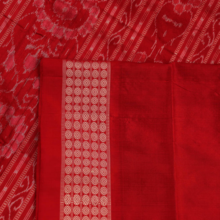 Close-up of green and orange silk Sambalpuri saree fabric with intricate motif patterns