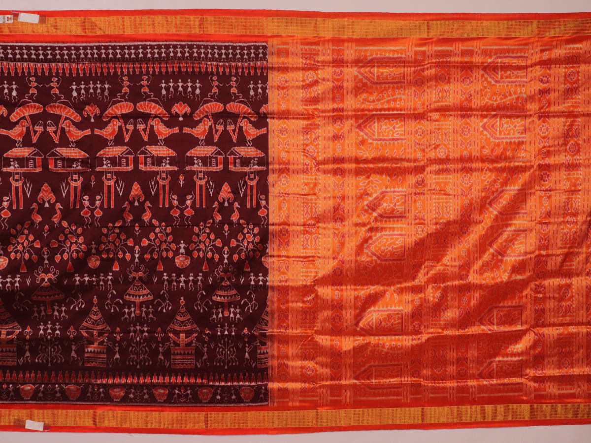 Close-up of maroon and orange Sambalpuri silk saree fabric texture, showcasing handloom weave and motif details.