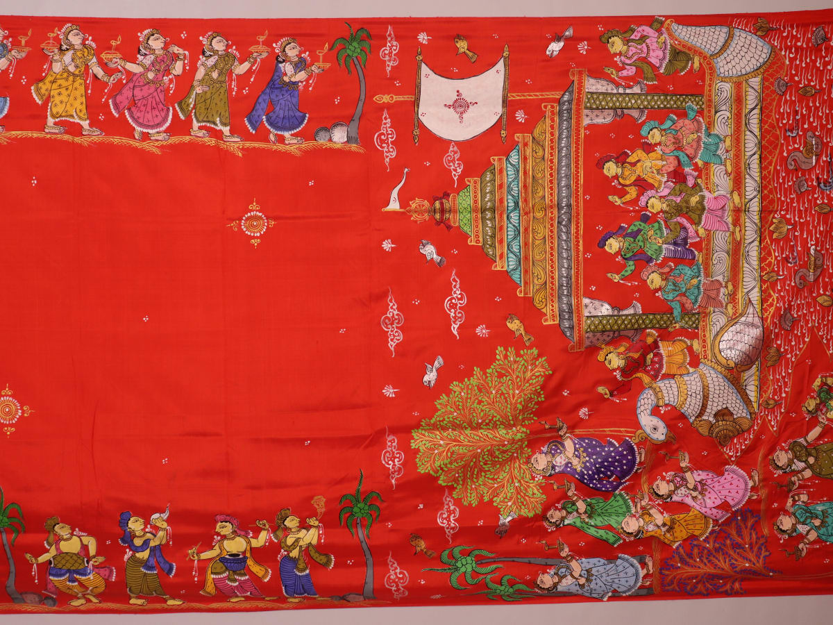 Close-up of red Patachitra silk saree fabric showing hand-painted texture.