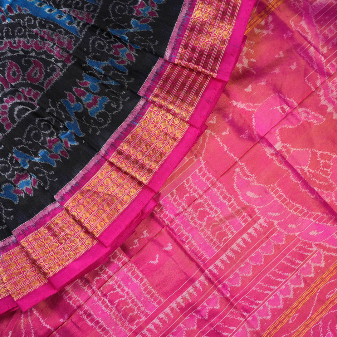 Close-up revealing the sheer tissue silk texture of the black saree, with subtle shimmering pink motifs.