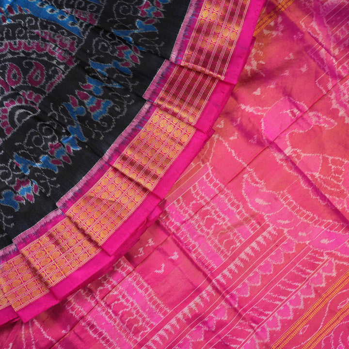 Close-up revealing the sheer tissue silk texture of the black saree, with subtle shimmering pink motifs.