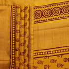 Close-up of the yellow printed Tussar silk saree's distinct slubby fabric texture.