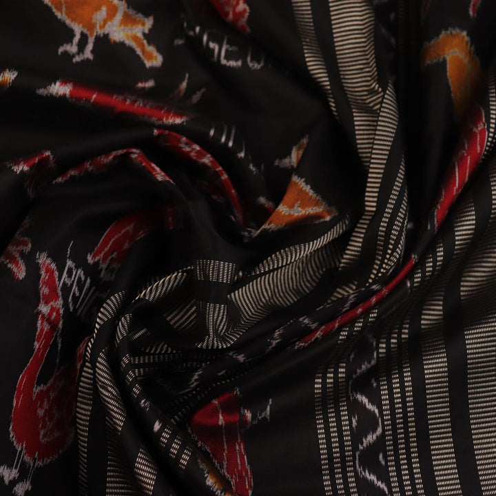 Close-up of the textured silk fabric of a black Sambalpuri saree showing intricate motifs.