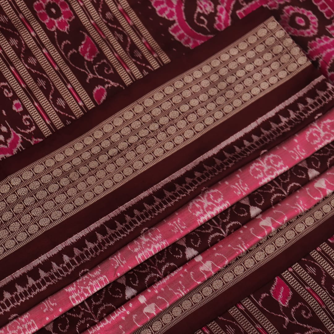 Close-up of peach and maroon Sambalpuri silk saree fabric showing intricate handloom texture and motifs.