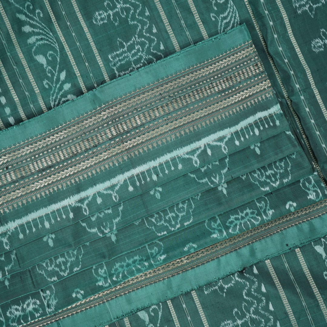 Close-up of green Sambalpuri silk fabric, showing its luxurious texture and fine handloom weave.