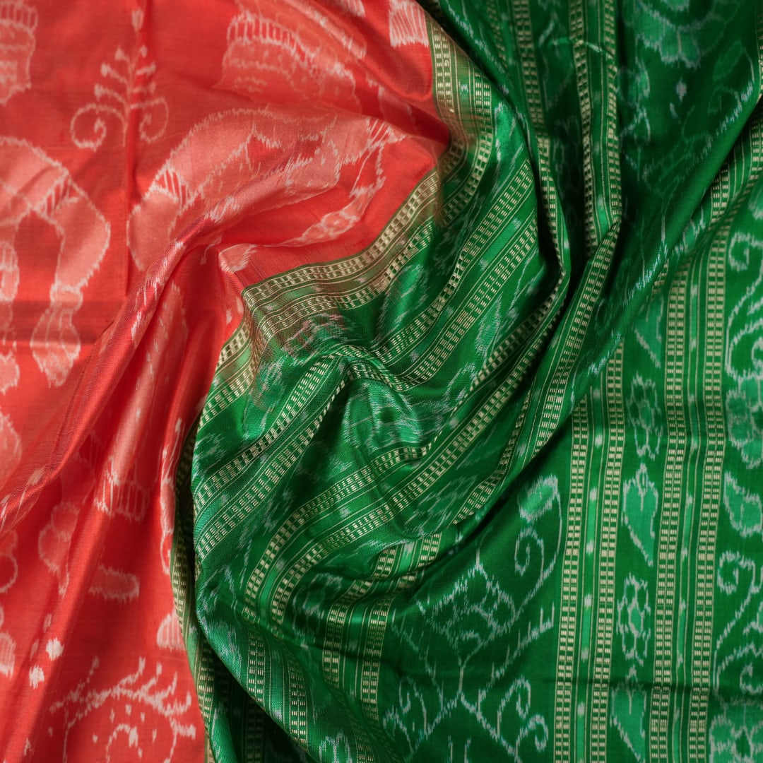 Close-up of the smooth, rich silk texture of the peach Sambalpuri saree with fine motifs.