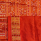 Close-up of maroon and orange Sambalpuri silk saree fabric texture, showcasing handloom weave and motif details.