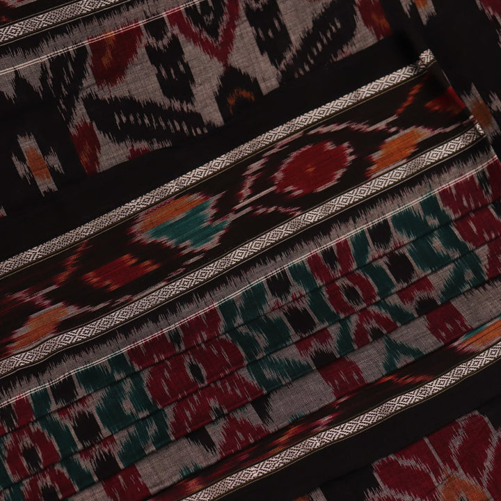 A woman draped in a grey and black cotton Sambalpuri saree, showcasing intricate motifs on the pallu and body.