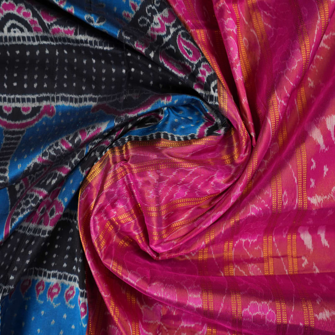 Close-up revealing the sheer tissue silk texture of the black saree, with subtle shimmering pink motifs.