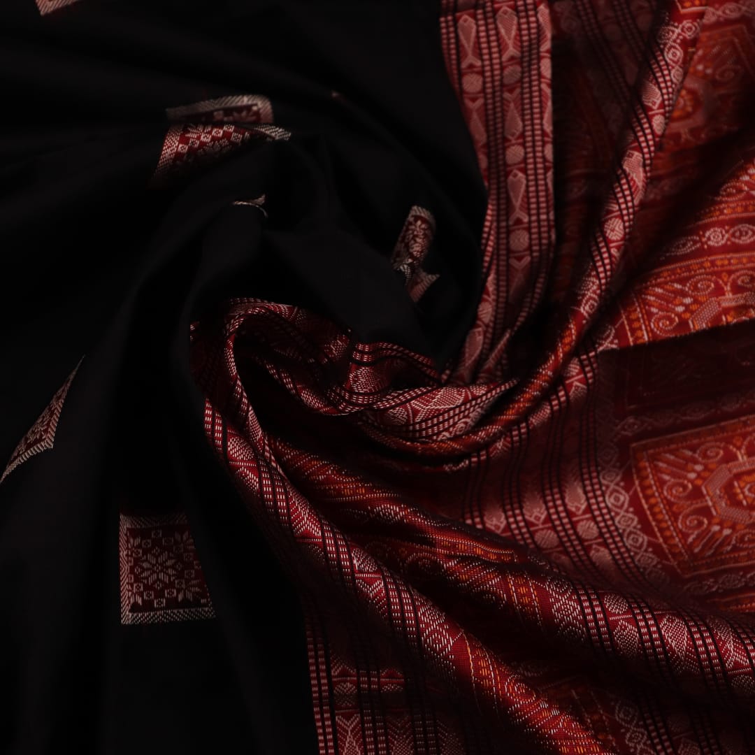 Close-up of black and red silk Sambalpuri saree fabric showcasing intricate motifs