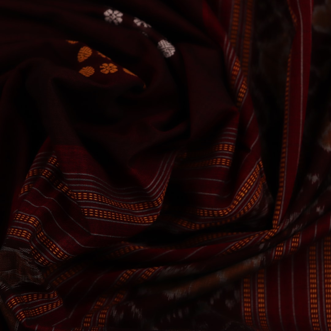 Full view of a maroon cotton Bomkai saree featuring a butta pattern with a red border and pallu.