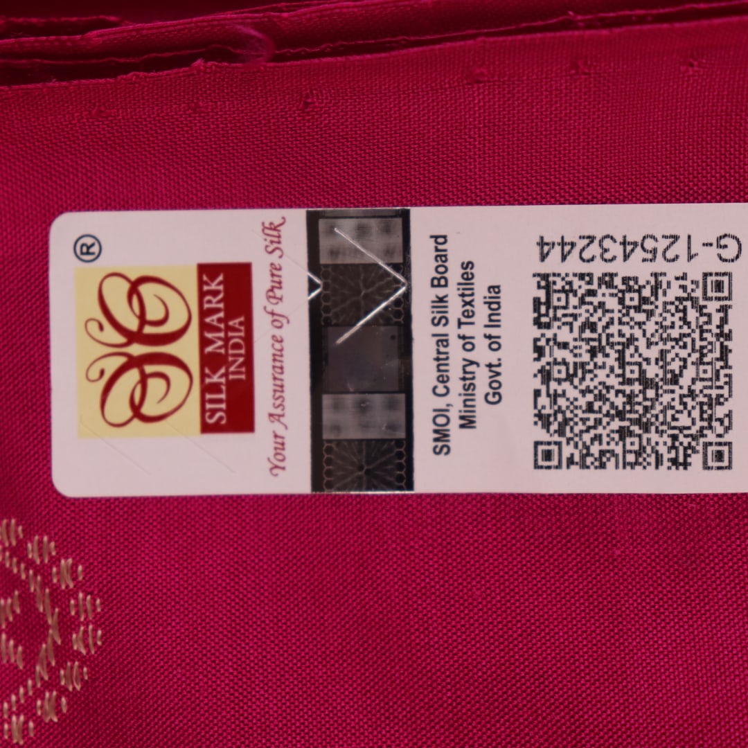 Close-up of green and magenta Bomkai silk saree fabric texture, highlighting intricate weave and butta pattern.