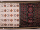 Close-up of handloom Sambalpuri silk saree fabric texture; white with subtle black motifs.