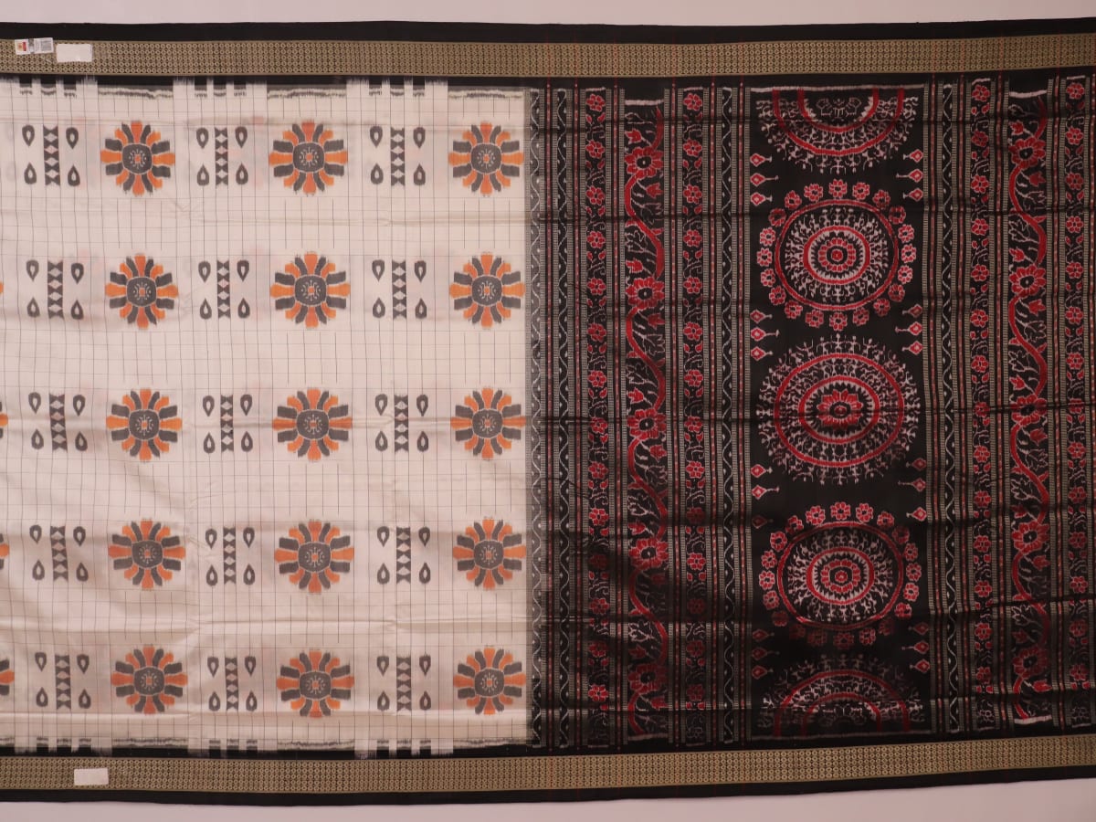 Close-up of handloom Sambalpuri silk saree fabric texture; white with subtle black motifs.