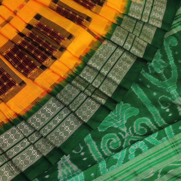 Close-up of yellow Sambalpuri silk saree fabric showing intricate motifs and woven texture.