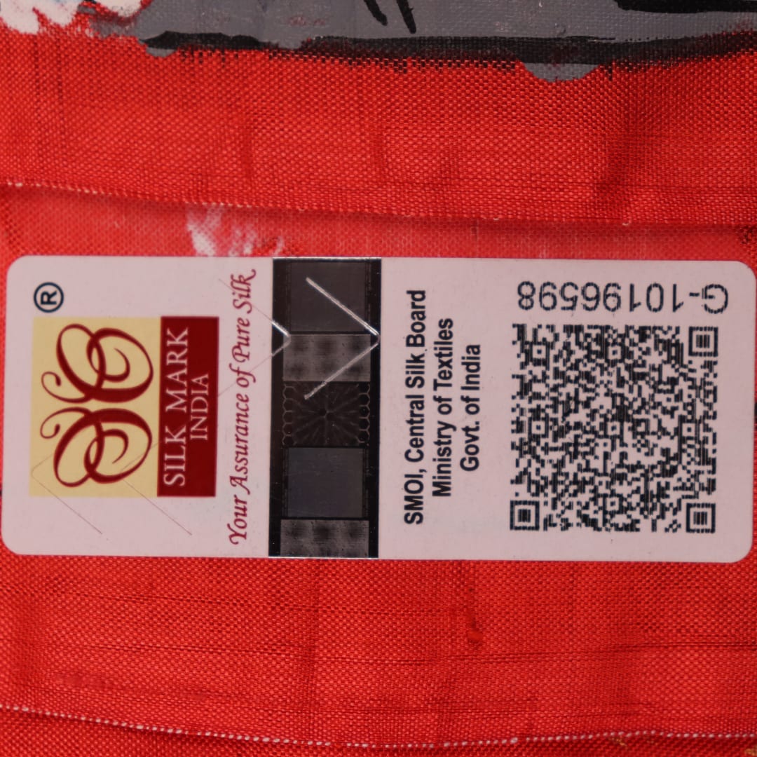 Close-up of red Patachitra silk saree fabric showing hand-painted texture.