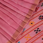 Close-up view of the smooth, textured tussar silk fabric in a delicate pink hue, showcasing the intricate butta pattern.