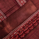 Close-up of maroon Tussar silk saree fabric, revealing its characteristic slub texture and printed details.