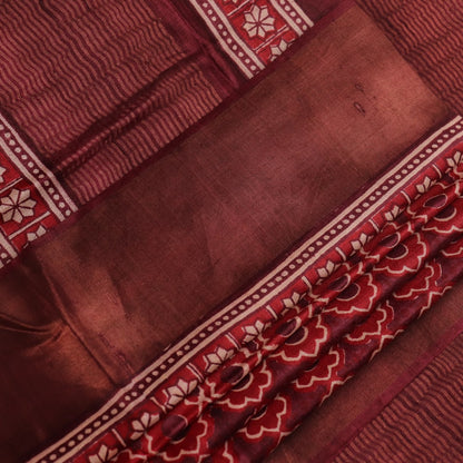 Close-up of maroon Tussar silk saree fabric, revealing its characteristic slub texture and printed details.