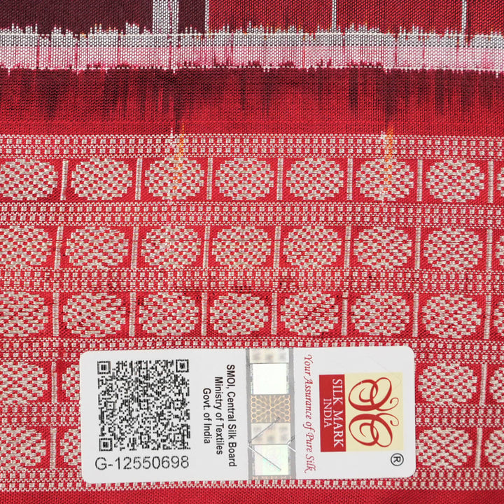 Close-up of the maroon Sambalpuri silk saree fabric, highlighting its luxurious texture and intricate weave.