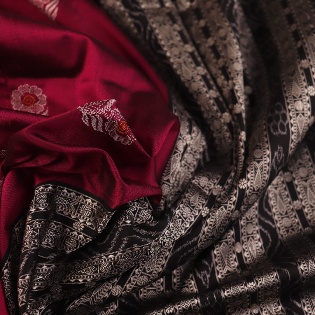 Close-up of magenta and black Bomkai silk saree texture, showing butta pattern weave.