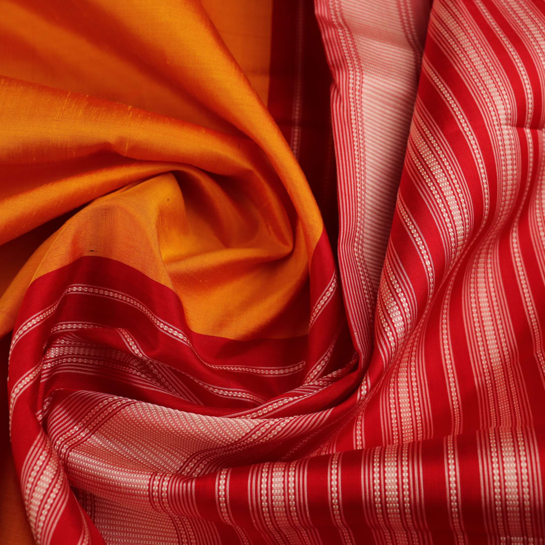 Close-up view of the smooth and lustrous silk fabric texture in a plain yellow Berhampuri saree.