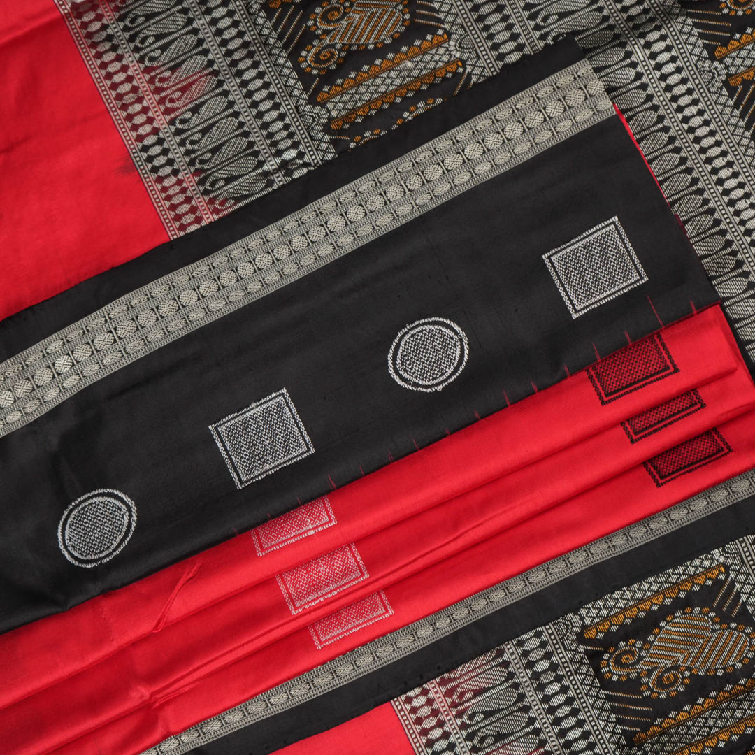 Extreme close-up of red Bomkai silk saree fabric showcasing rich texture and intricate weave.