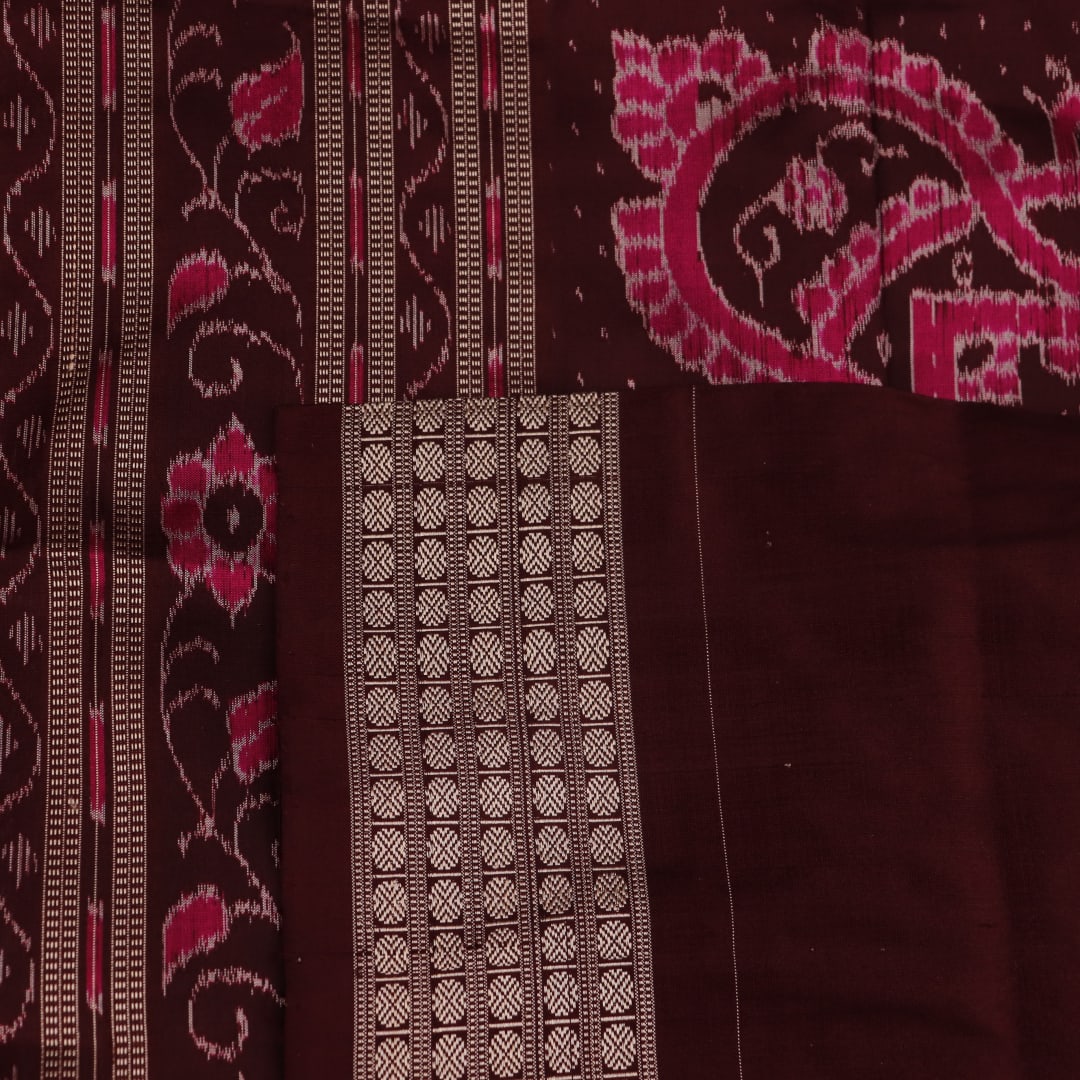 Close-up of peach and maroon Sambalpuri silk saree fabric showing intricate handloom texture and motifs.