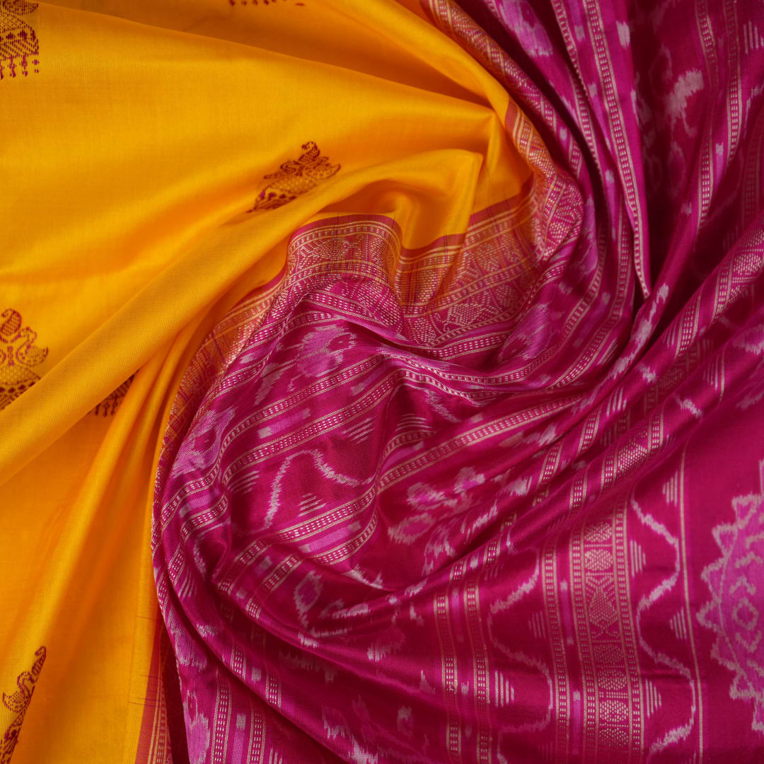 Close-up of the Bomkai Silk Saree's yellow fabric, revealing its luxurious texture and handloom weave.