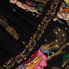 Close-up of black silk Patachitra saree fabric texture showing hand-painted details.