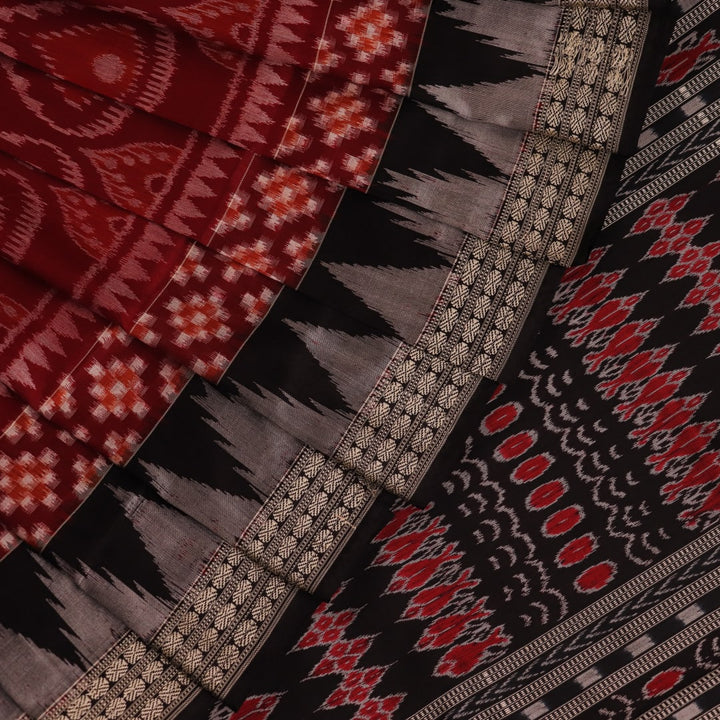 Close-up view of maroon and black silk Sambalpuri saree fabric showcasing intricate motifs