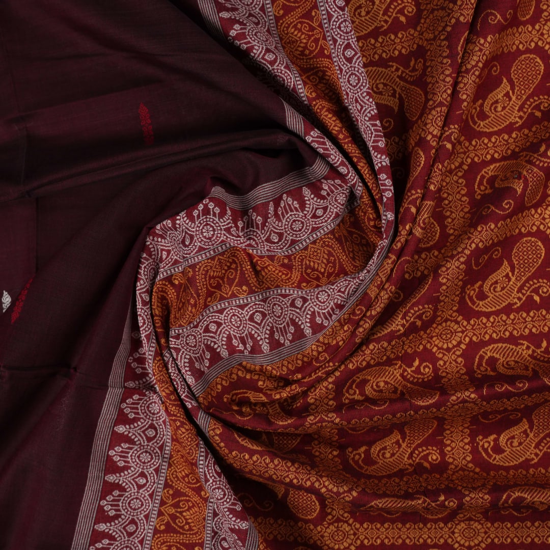 Full view of the maroon Bomkai cotton saree with red borders and small butta motifs laid out flat.