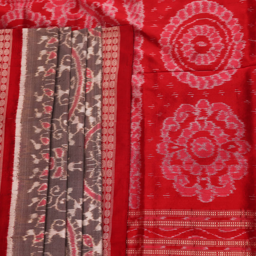 Close-up of grey Sambalpuri silk saree fabric showing intricate motif texture.