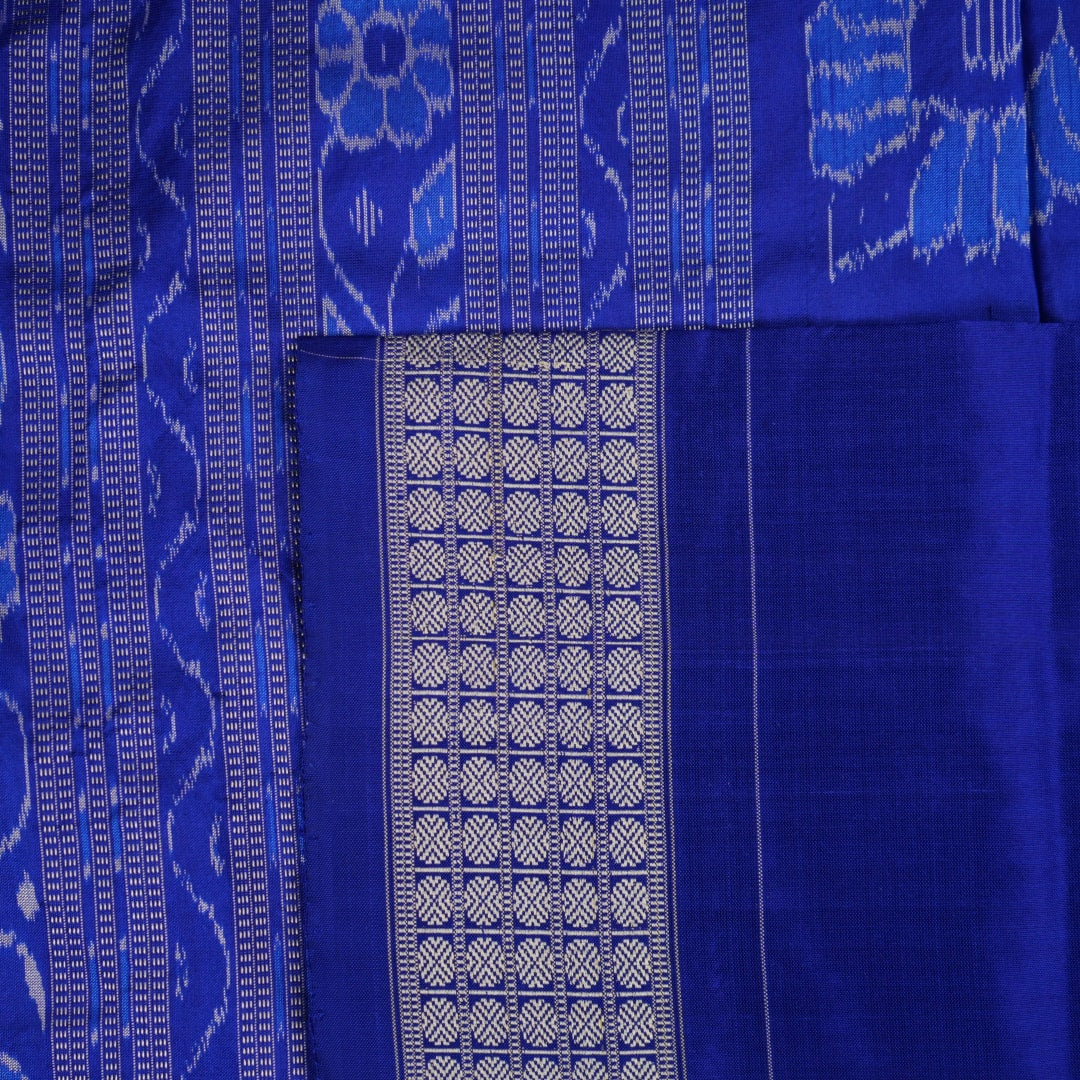 Extreme close-up of the grey and blue Sambalpuri silk saree fabric, revealing its rich texture and intricate weave.