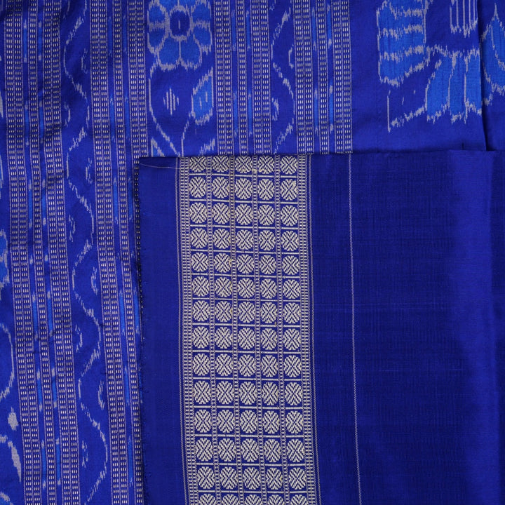 Extreme close-up of the grey and blue Sambalpuri silk saree fabric, revealing its rich texture and intricate weave.
