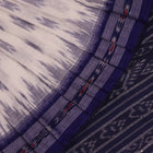 Model wearing a white Sambalpuri cotton saree with blue motifs, showcasing the drape and overall look.