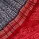 Close-up of grey and red Sambalpuri silk saree fabric showing intricate woven motif texture.