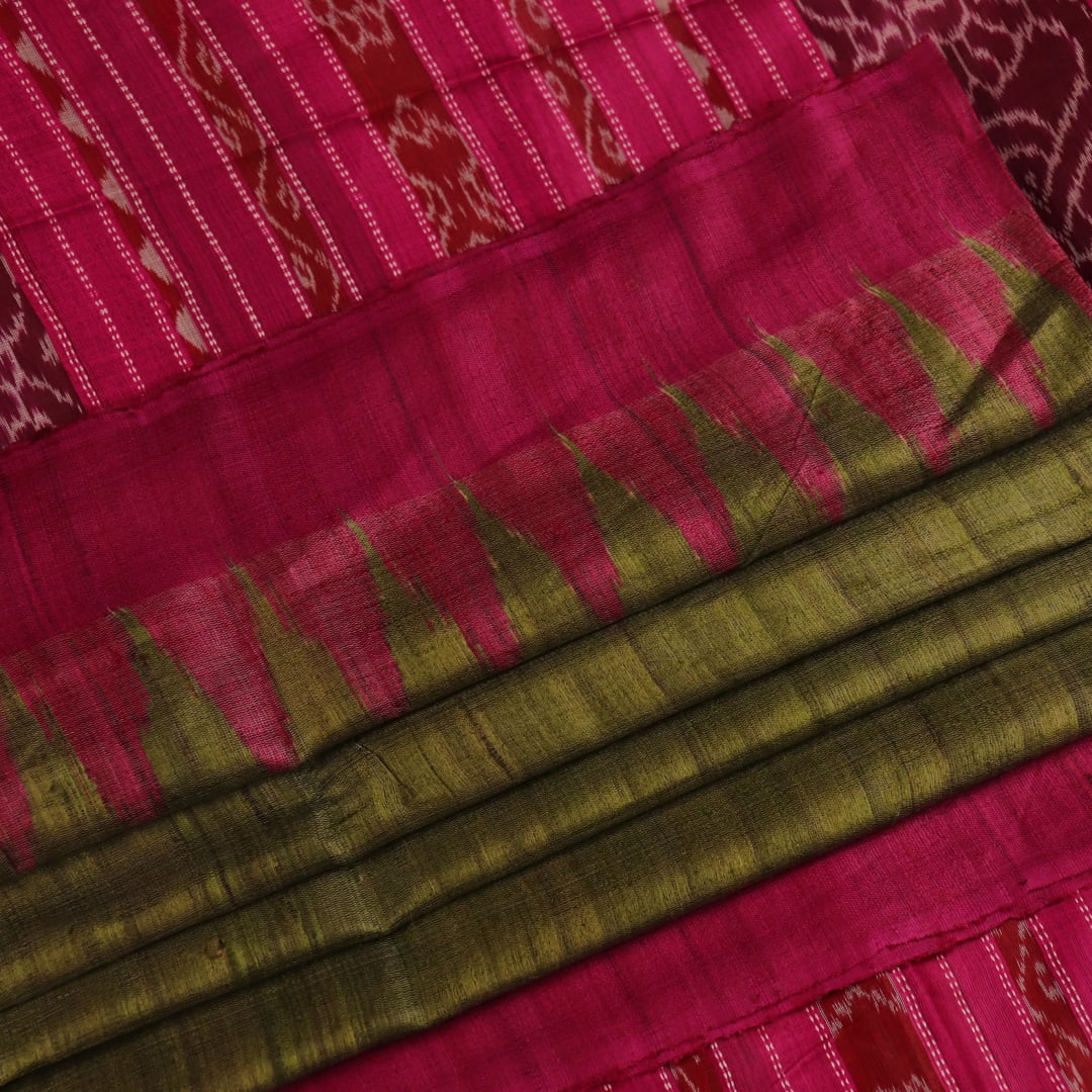 Close-up view of the luxurious texture of a plain green Tussar silk saree with a magenta border