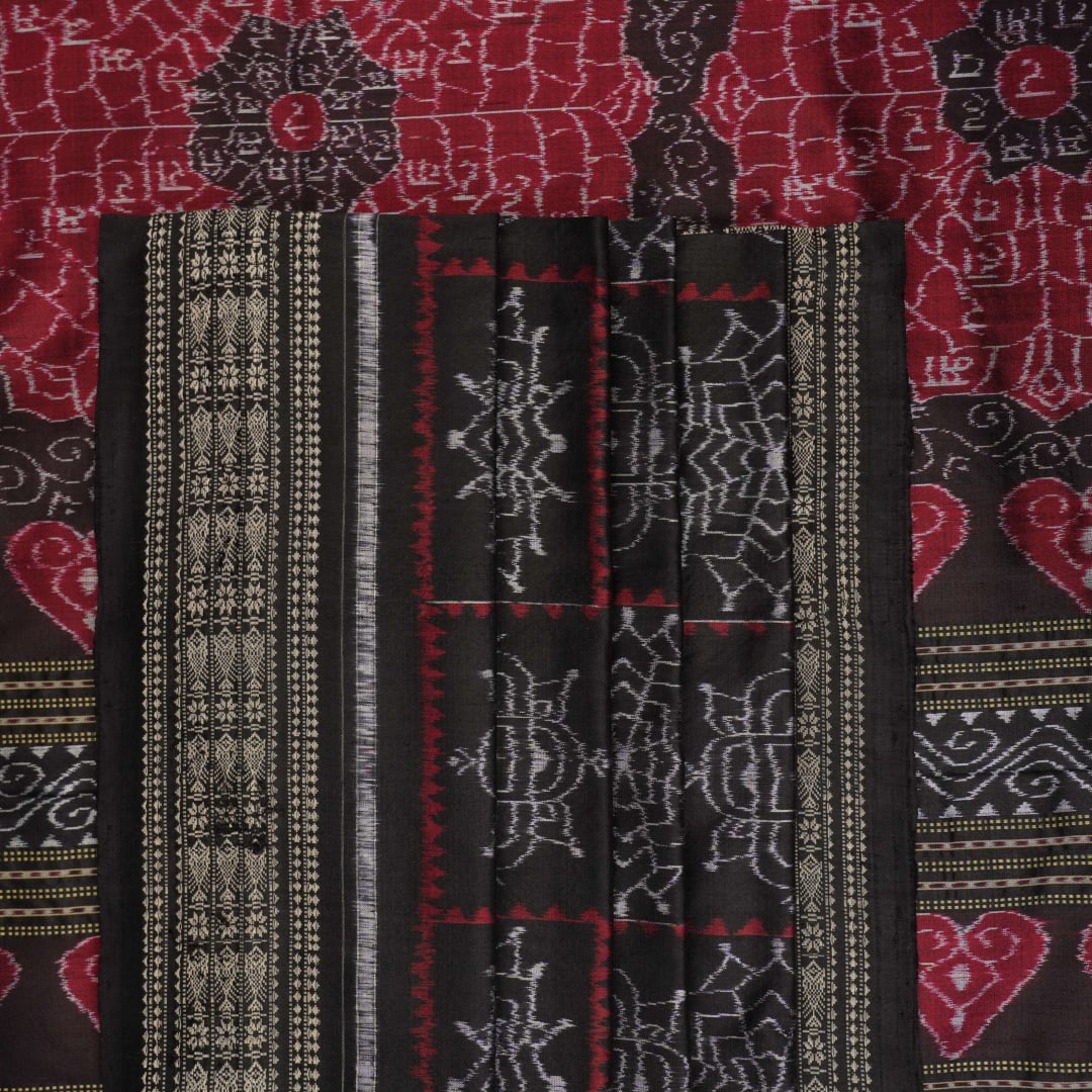 Extreme close-up of black Sambalpuri silk saree fabric, highlighting its luxurious texture and weave.