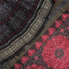 Extreme close-up of black Sambalpuri silk saree fabric, highlighting its luxurious texture and weave.