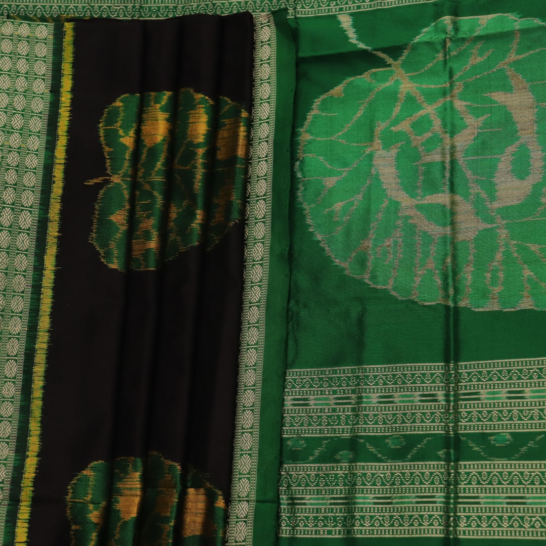 Close-up of the finely textured silk fabric in black, adorned with intricate Sambalpuri motifs in green