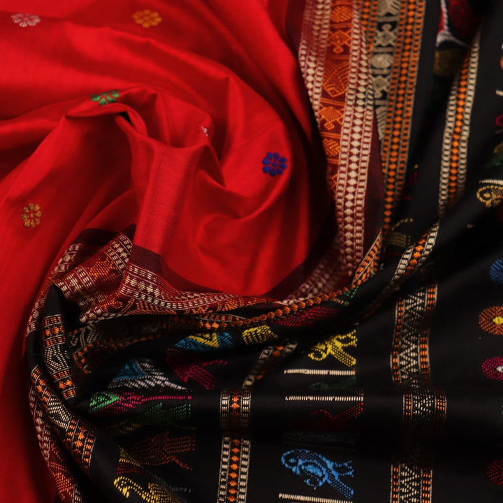 Close-up view of the soft and lustrous silk fabric texture of a Dolabedi red and black handloom saree with a butta pattern.