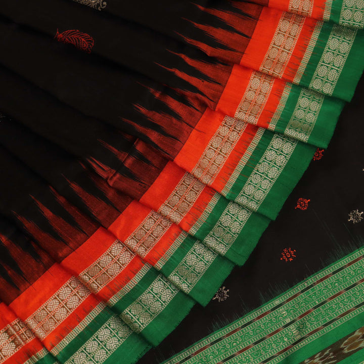 Close-up view of black silk Bomkai saree fabric showcasing its intricate butta pattern.