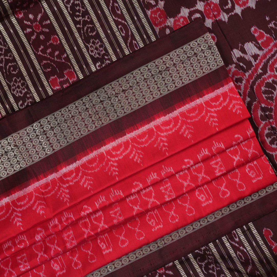 Ultra close-up of the red Sambalpuri silk saree fabric, revealing its luxurious texture and handloom weave.
