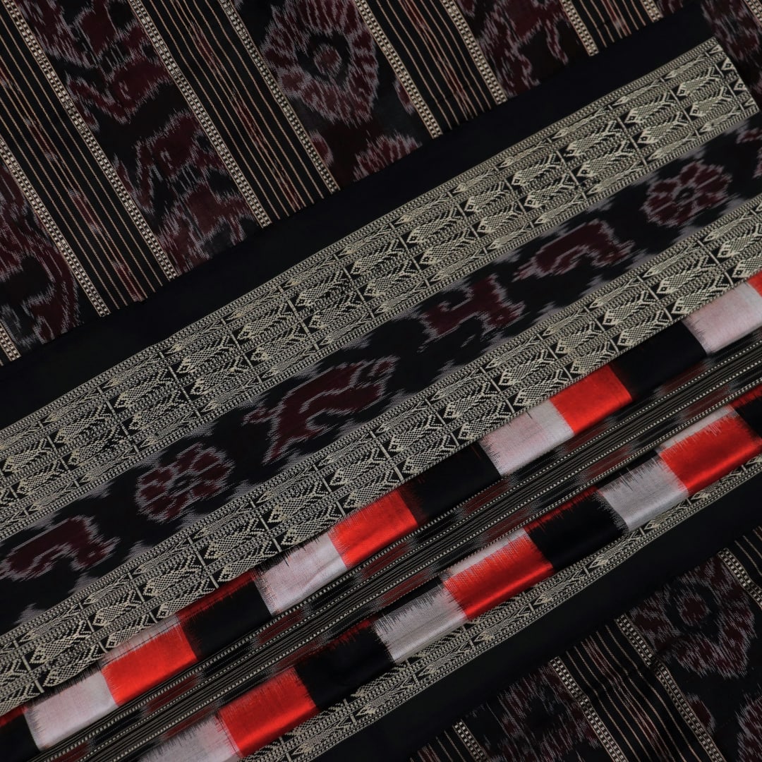 Close-up view of the smooth, lustrous texture of black silk fabric with a Pasapalli pattern in the Sambalpuri style