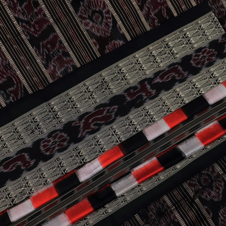 Close-up view of the smooth, lustrous texture of black silk fabric with a Pasapalli pattern in the Sambalpuri style