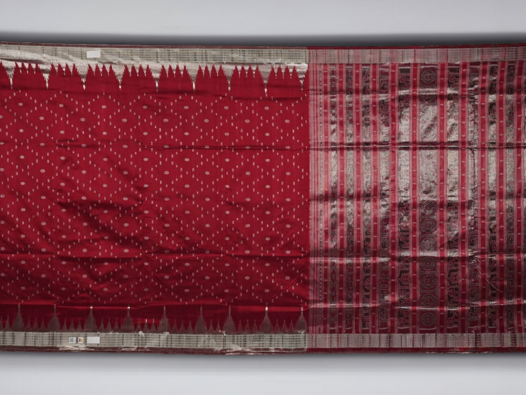 Extreme close-up revealing the rich texture and intricate handloom weave of the maroon and grey Sambalpuri silk fabric.