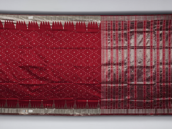 Extreme close-up revealing the rich texture and intricate handloom weave of the maroon and grey Sambalpuri silk fabric.