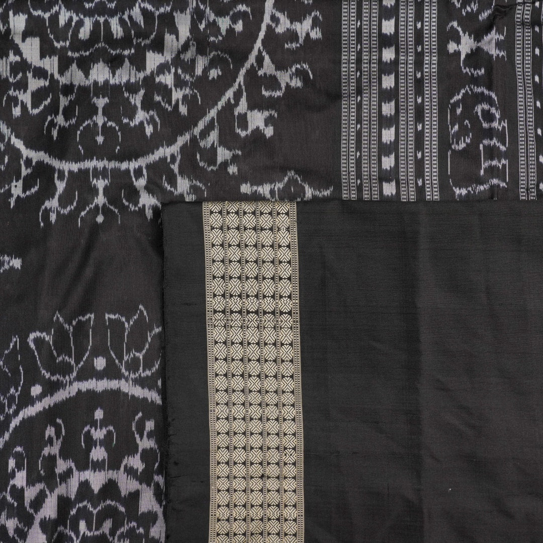 Close-up of grey & black Sambalpuri silk saree fabric, highlighting its rich texture and weave.